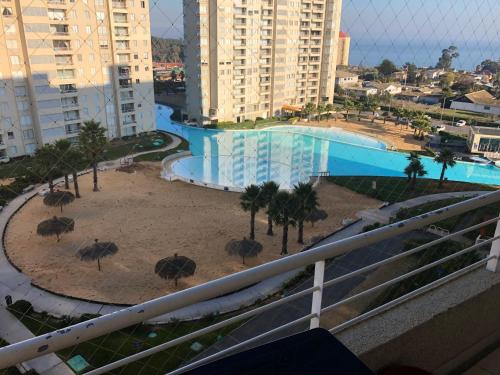 a view of a swimming pool with umbrellas and palm trees at Vista Laguna Apartment in Algarrobo