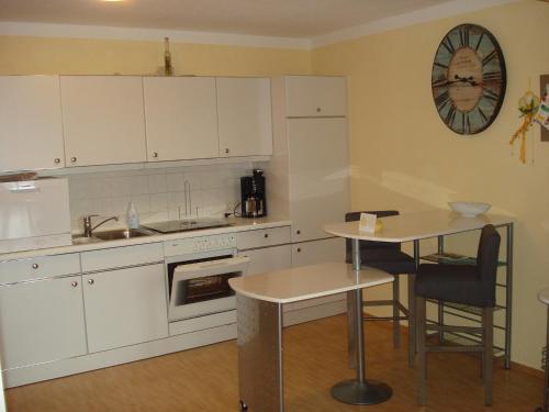 a kitchen with white cabinets and a small table at Haus Hönigsgrub in Rinchnach