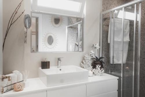 a white bathroom with a sink and a mirror at Sea view super romantic apartment in Athens