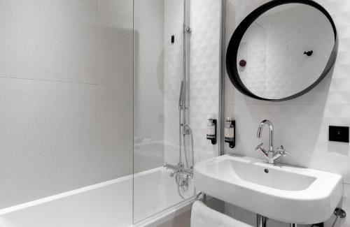 a white bathroom with a sink and a mirror at Hôtel Montmorency & Spa in Carcassonne
