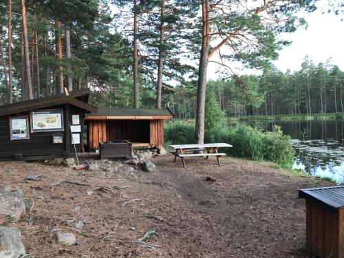 a cabin with a picnic table next to a lake at Täppans B&B in Ålberga