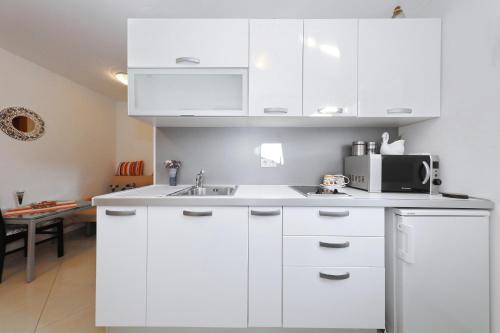 a white kitchen with a sink and a microwave at Senkini Dvori in Sutomišćica