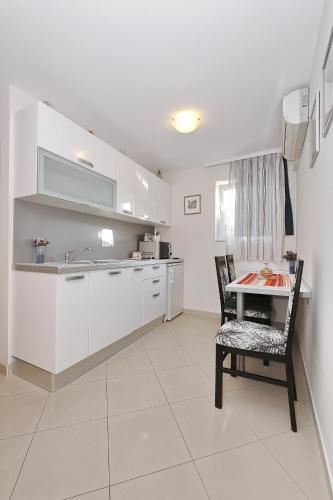a kitchen with white cabinets and a table and chairs at Senkini Dvori in Sutomišćica