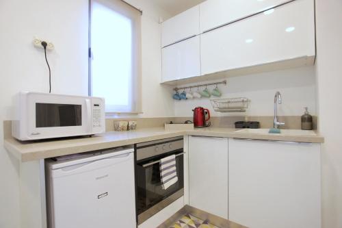 a white kitchen with white cabinets and a microwave at Modern Home In The Heart of Nachlaot in Jerusalem