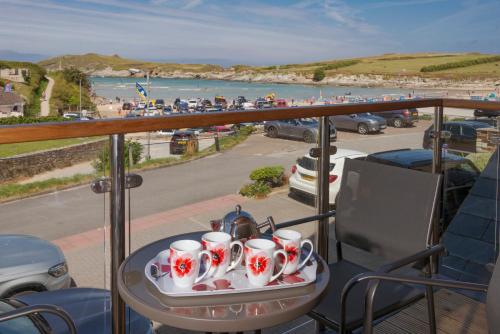 a tray of tea cups on a table on a balcony with a beach at The Beach House & Porth Sands Apartments in Newquay