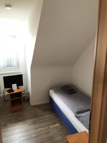 a small bedroom with a bed and a desk at Hotel Sonnenhof in Sindelfingen
