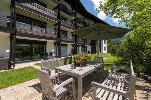 einen Holztisch mit einem Regenschirm und zwei Stühlen in der Unterkunft Apartment Tgesa La Roiva mit Hallenbad und Sauna in Lenzerheide