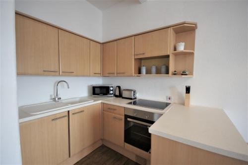 una cocina con armarios de madera y fregadero en Bright and Cosy West End Apartment, en Glasgow