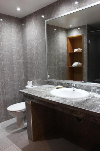 a bathroom with a sink and a toilet and a mirror at Hotel Club Almoggar Garden Beach in Agadir