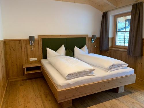 a bedroom with a bed with white pillows and a window at Kererhof in Kals am Großglockner