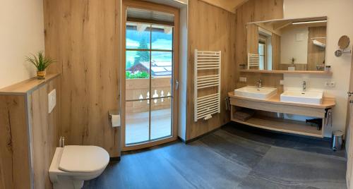 a bathroom with two sinks and a toilet and a mirror at Kererhof in Kals am Großglockner