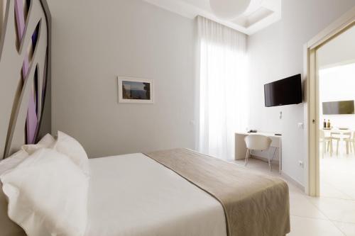 Dormitorio blanco con cama y mesa en Dioniso’s Luxury Apartments Municipio, en Nápoles