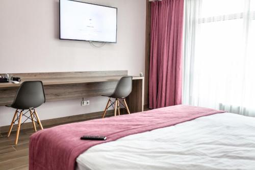 a bedroom with a bed and two chairs and a tv at Aleanda in Chernivtsi