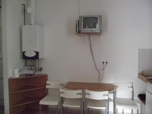 a dining room table with chairs and a tv on the wall at Sárkány Apartman, Sárkány Wellness és Gyógyfürdő in Nyírbátor