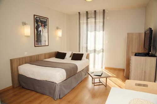 ein Hotelzimmer mit einem Bett und einem TV in der Unterkunft Lagrange Aparthotel Toulouse Saint-Michel in Toulouse