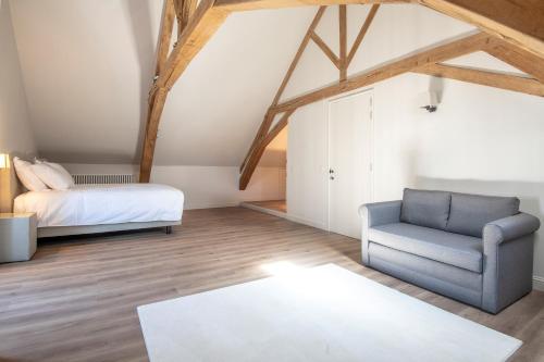 a bedroom with a bed and a couch and a chair at Bed & Breakfast Jezuietenplein 21 in Oudenaarde