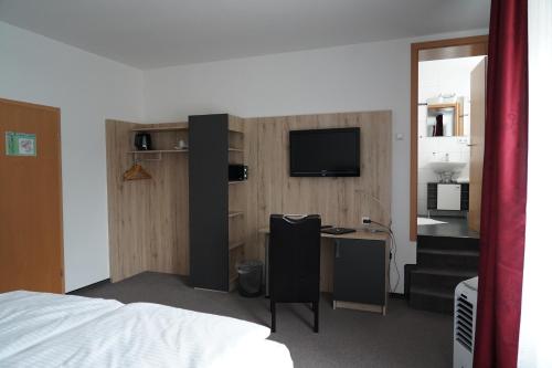 a bedroom with a bed and a desk with a television at Hotel & Restaurant Blume in Wolfsburg