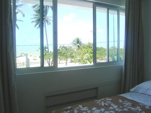 a bedroom with a window with a view of the beach at Apartamento Cabo Branco Beira-Mar in João Pessoa