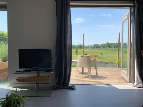 a living room with a tv and a large window at Mae Usu in Nieuw-Roden