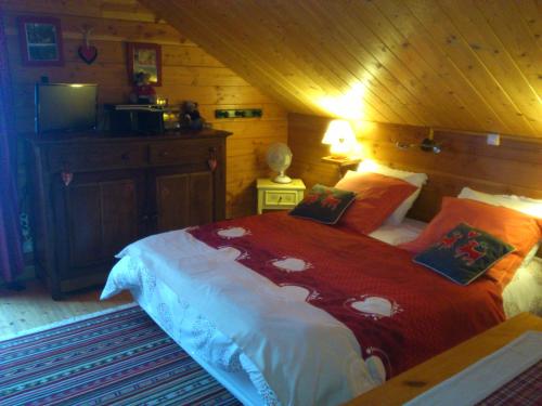- une chambre avec un grand lit et une couverture rouge dans l'établissement Chalet Gérardmer situé a LE THOLY, à Le Tholy