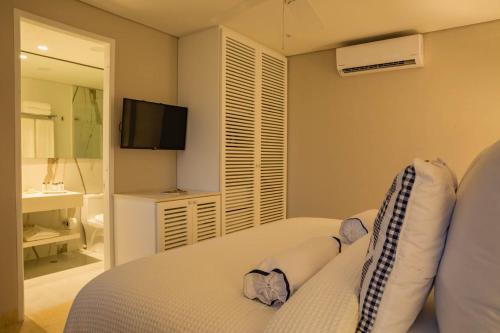 a bedroom with a white bed and a television at Casa La Merced by Mustique in Cartagena de Indias