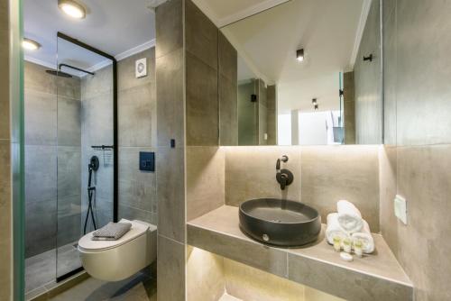 ein Bad mit einem Waschbecken, einem WC und einer Dusche in der Unterkunft Matala Luxury Apartments in Matala