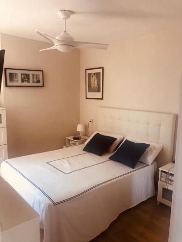 a bedroom with a white bed with a ceiling fan at Apartamento Urbanova in Arenales del Sol