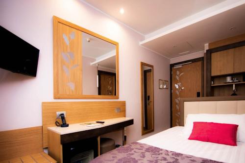 a bedroom with a bed and a desk and a mirror at Hotel Giolli Nazionale in Rome