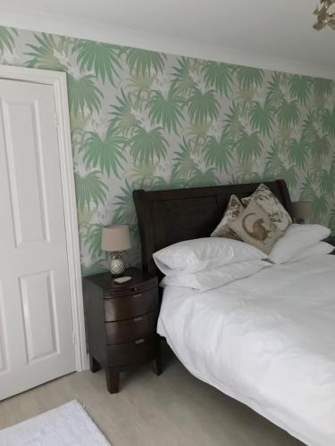 a bedroom with a bed with green palm wallpaper at Darceys in the Yard in Hornsea