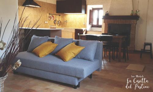 a blue couch with yellow pillows in a living room at La Casetta del Pàstine, Il Borgo Diffuso di San Michele in San Michele in Teverina