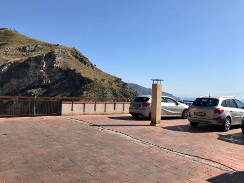 two cars parked in a parking lot next to a mountain at Little Paradise in Taormina