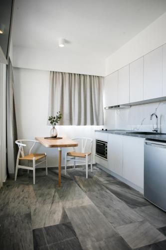 a kitchen with white cabinets and a table and chairs at Pharos Apartments in Gavrion