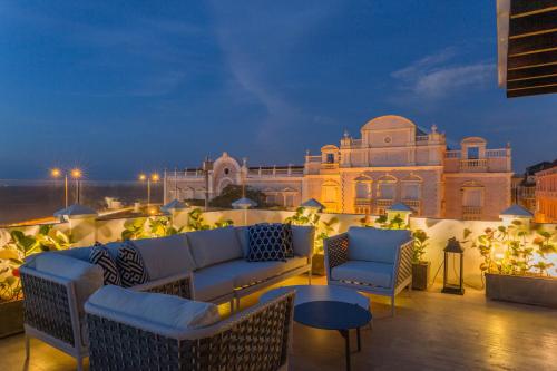 a rooftop patio with couches and tables and a building at Casa La Merced by Mustique in Cartagena de Indias