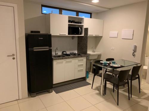a kitchen with a black refrigerator and a table with chairs at Flats Mobiliados Zona Norte, Casa forte, recife, Aluguel por temporada Direto com o dono in Recife
