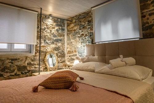 een slaapkamer met een groot bed en een stenen muur bij PETRA'S HOUSE in Kavala