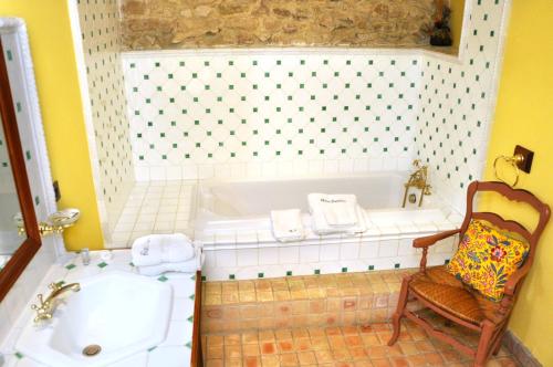 uma casa de banho com uma banheira, uma cadeira e um lavatório. em Chambres d'hôtes Château de Jonquières em Narbona