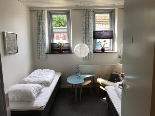 Cette petite chambre comprend deux lits et une table. dans l'établissement Ibsens Gaard, à Ebeltoft