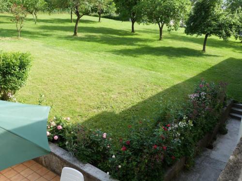 a green umbrella in a garden with a field of flowers at Ancienne Fermette le Charlemont Givet Foisches in Foisches