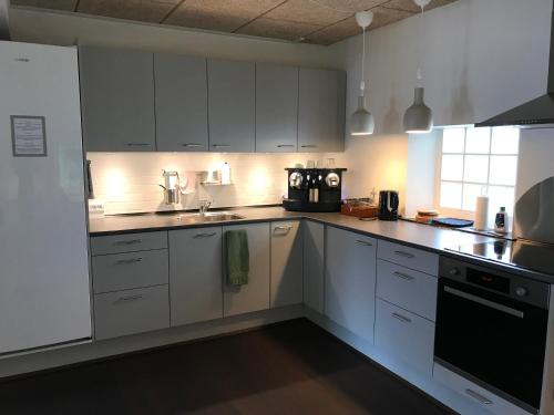 a white kitchen with white cabinets and a sink at Ibsens Gaard in Ebeltoft