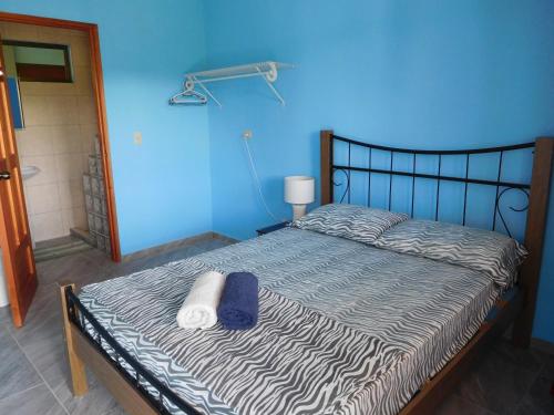 Cama en habitación con pared azul en Hostal Casa Las Lajas, en Las Lajas