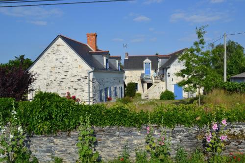 una casa blanca con una pared de piedra y flores en Gîte Dagueloire en La Daguenière