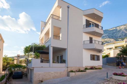 a white apartment building with balconies and mountains in the background at IvMaLu Apartments in Tučepi
