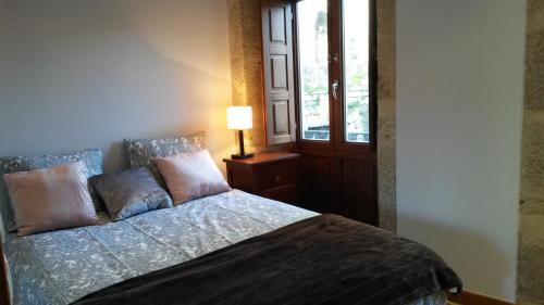 a bedroom with a bed and a lamp and a window at Apartamento con vistas a la catedral in Santiago de Compostela