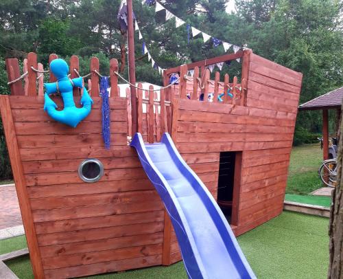 a wooden playground with a slide in a yard at zacisze in Junoszyno