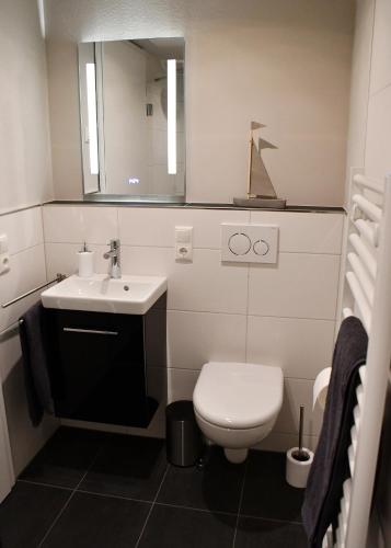 a bathroom with a toilet and a sink and a mirror at Zum Anker in Simmerath