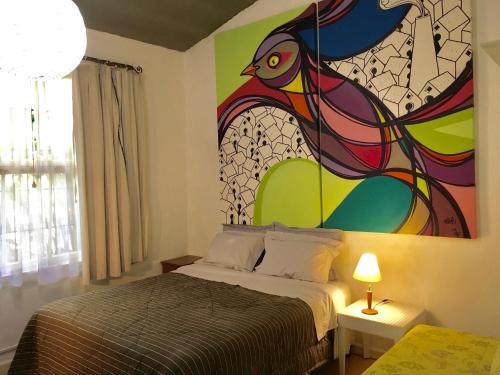 a bedroom with a bed with a painting on the wall at Residência Acolhedora in Porto Alegre