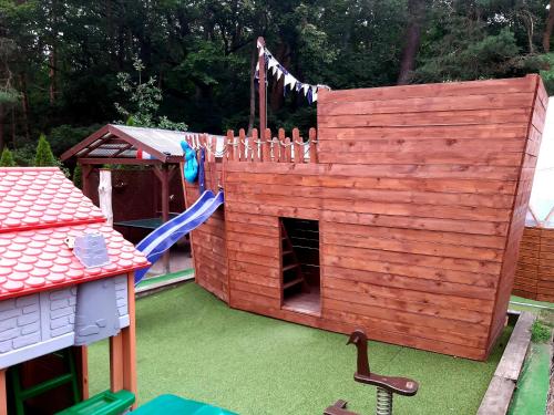 una casa de juegos de madera con un tobogán y un parque infantil en zacisze en Junoszyno