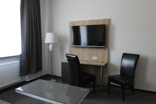 a hotel room with a desk with two chairs and a television at Hotel & Restaurant Blume in Wolfsburg