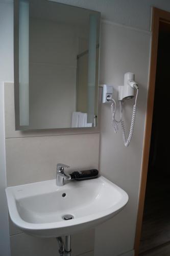 a bathroom with a white sink and a phone at Hotel Tini in Bad Fallingbostel