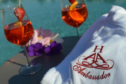 three glasses of wine on a table with flowers at Hotel Ambassador in Levico Terme